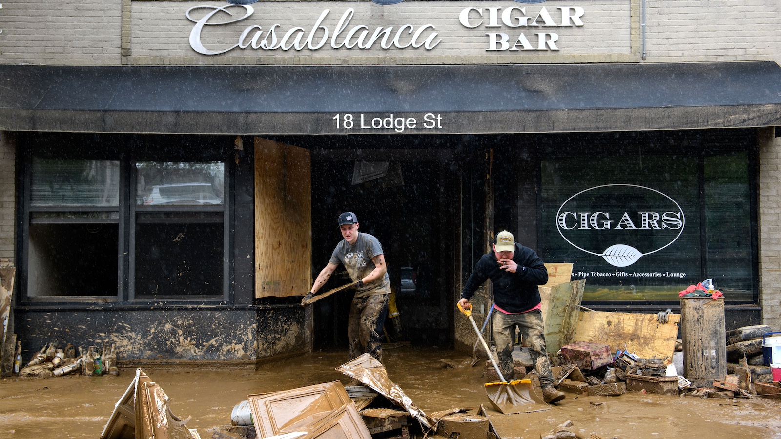 Two men remove mud and debris from their business in Asheville, which was inundated with floodwaters in the wake of Hurricane Helene.