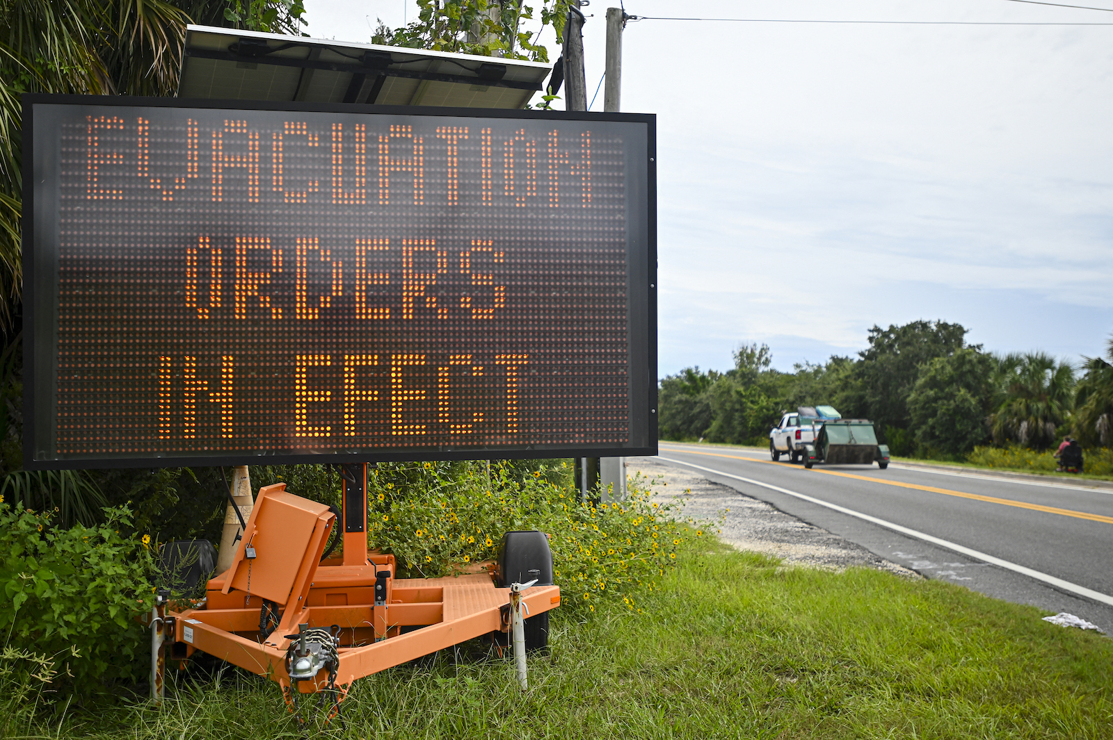 A large sign saying 'evacuation orders in effect' near a freeway