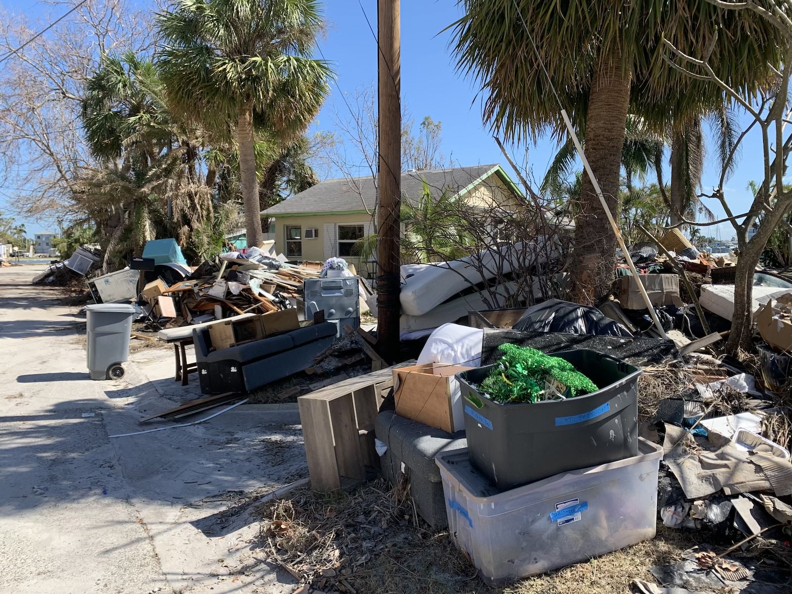 A pile of damaged furniture and wood line a residential street after a hurricane