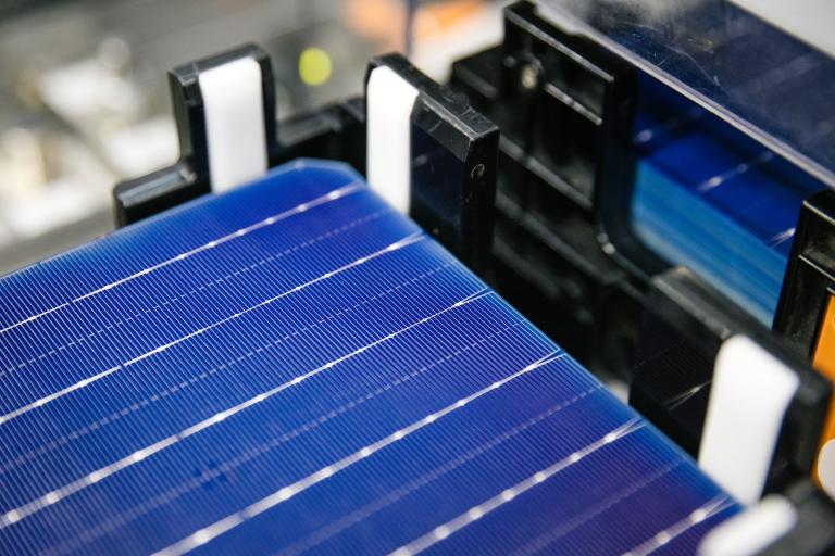 Close-up image of a deep blue solar panel with silver horizonal lines on it, on black equipment