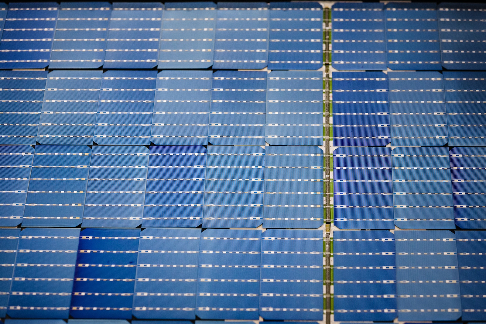 Overhead view of an array of approximately 36 blue solar panels, each with silver detailing