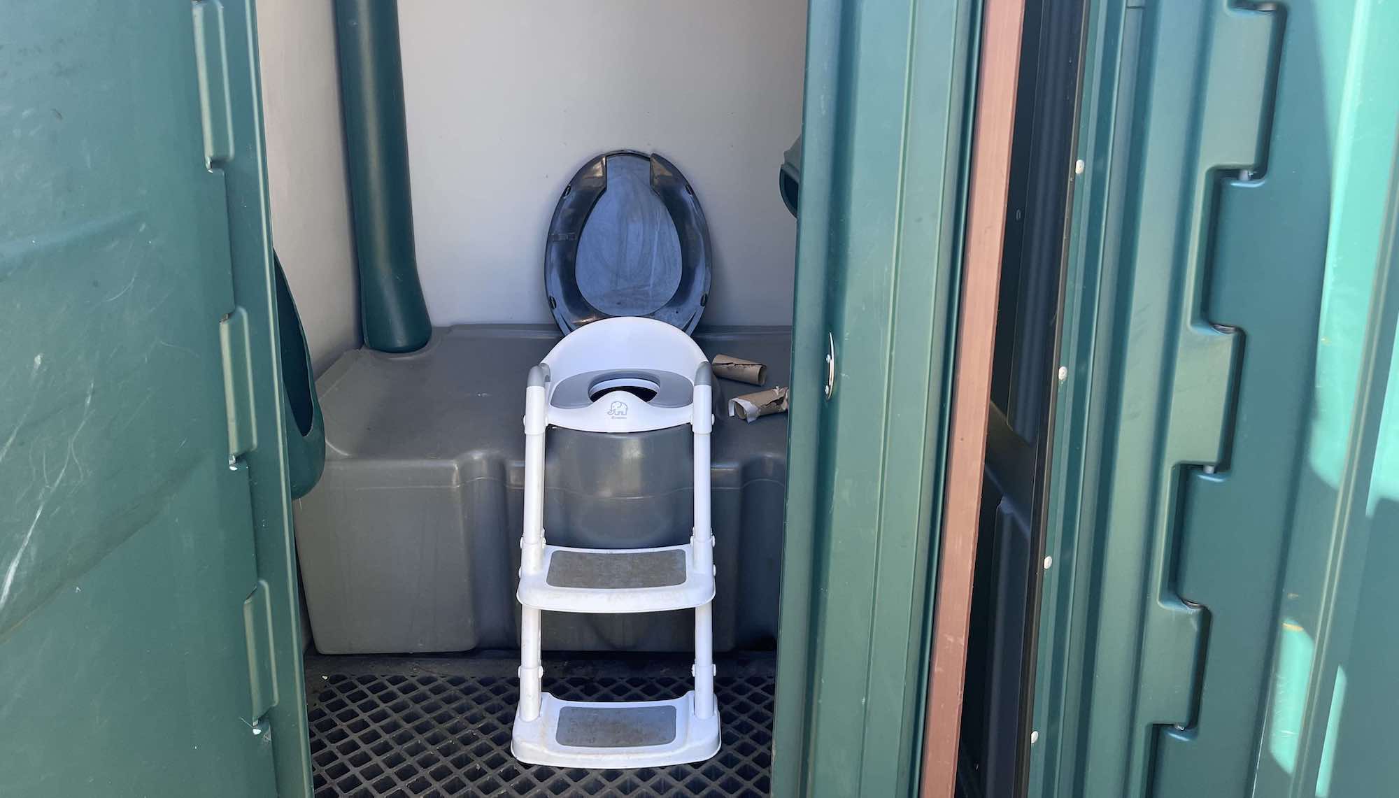 a white child-size potty chair inside a porta potty