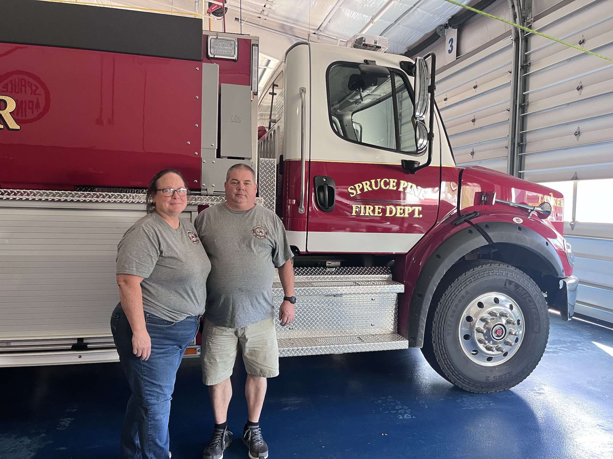 two people stand near a firetruck