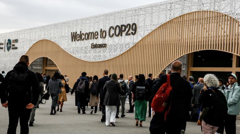 Participants walk by an entrance of COP29, UN Climate Change Conference venue, an event held by UNFCCC in Baku Olympic Stadium.