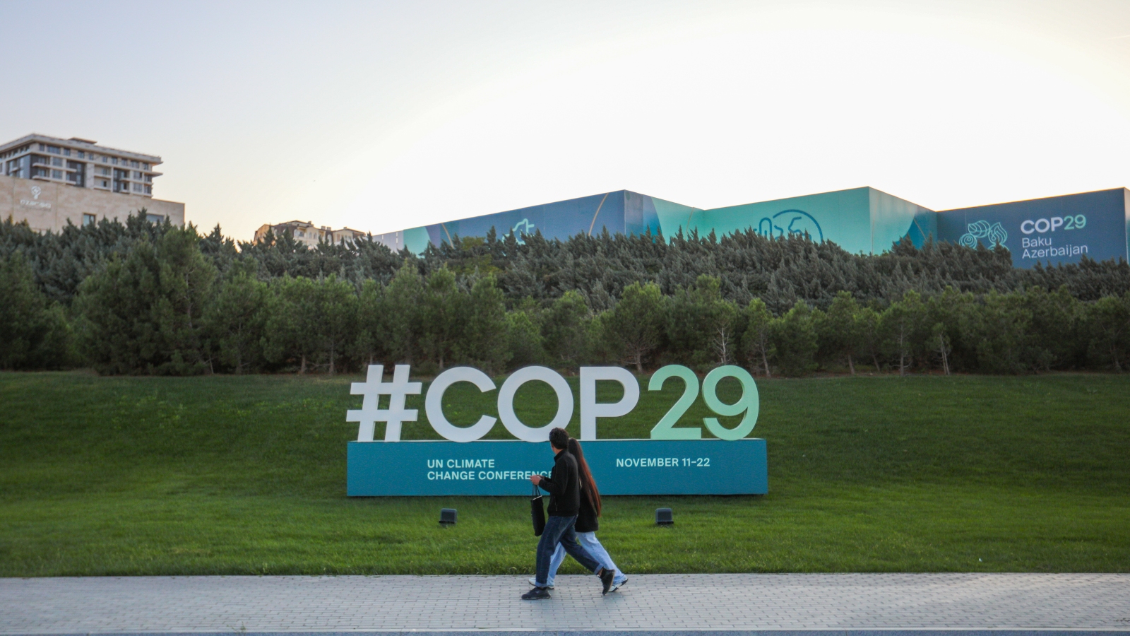 Citizens walks near a sign for COP29 near the Baku Olympic Stadium, the venue of the COP29 United Nations Climate Change Conference on October 23, 2024 in Baku, Azerbaijan.