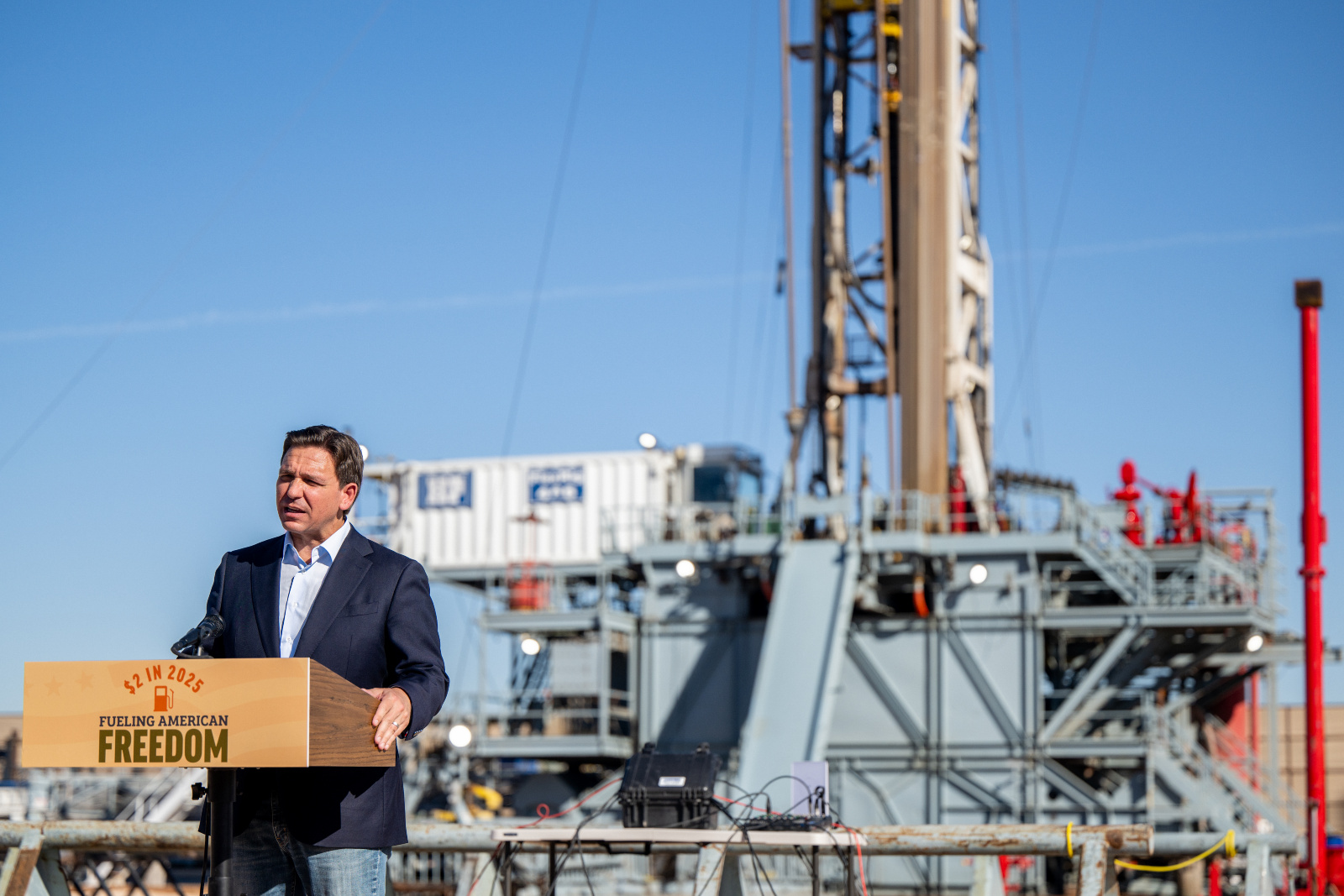 Photo of Ron Desantis speaking in front of a large oil rig