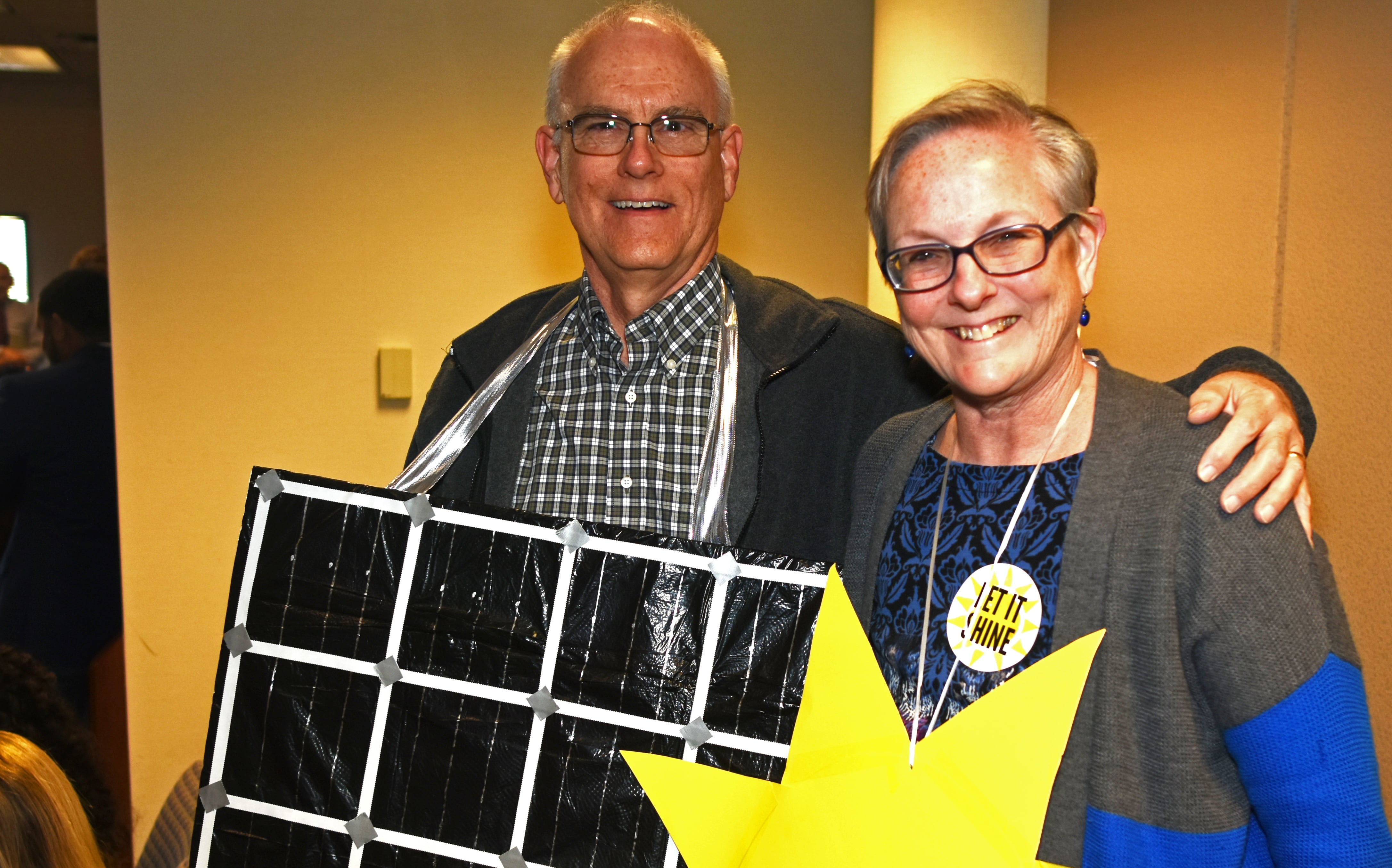 An elderly couple is dressed up as solar panels and as the sun