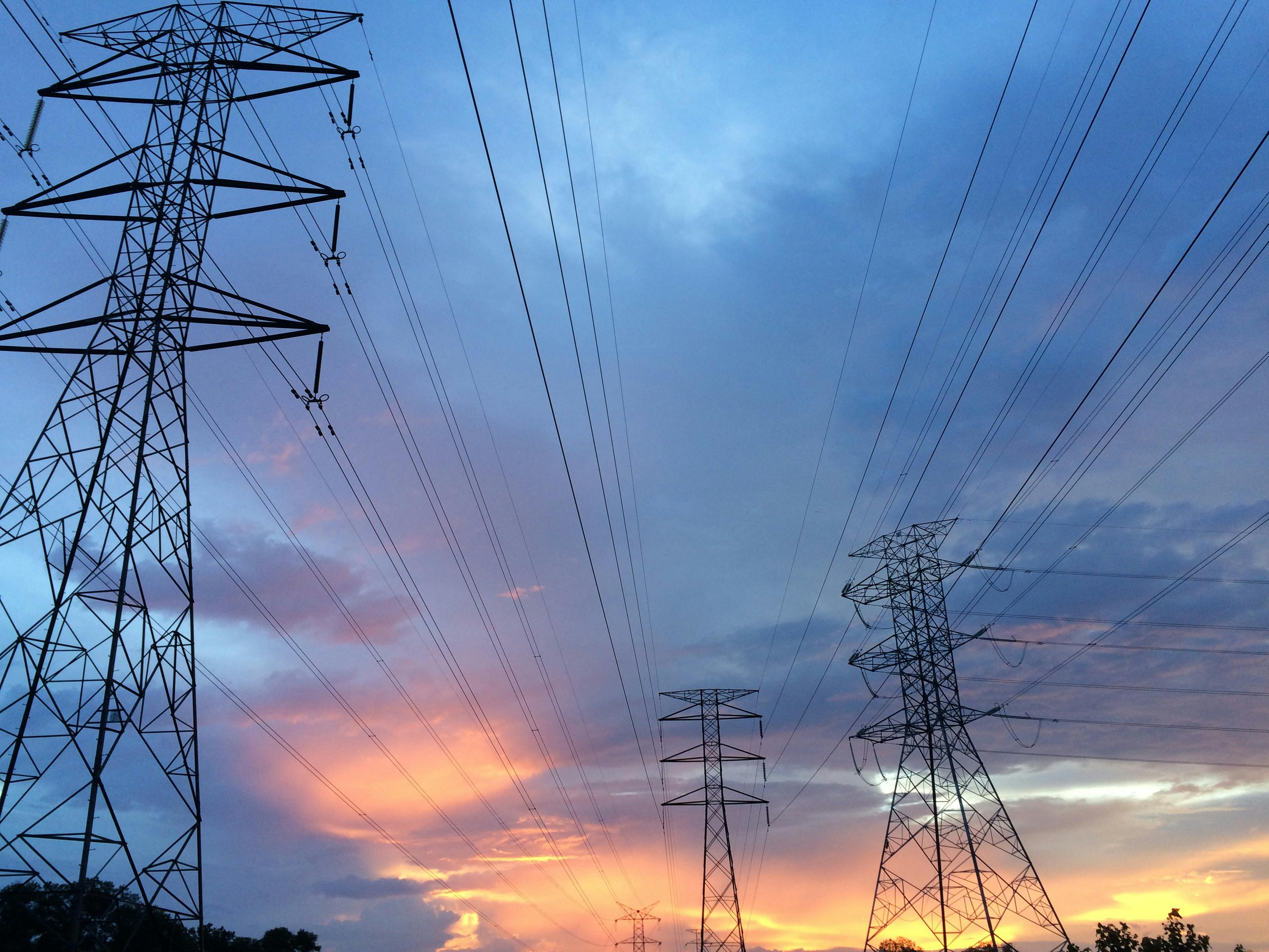 A powerline stands in front of blue and purple and orange sky