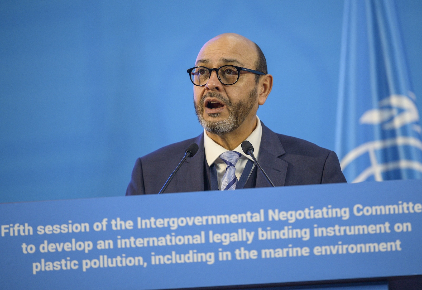 INC-5 Chair Luis Vayas Valdivieso stands at a blue lectern