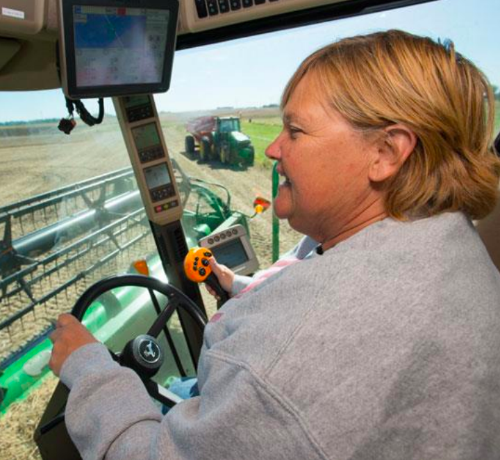 A woman drives a piece of farm equipment through a field