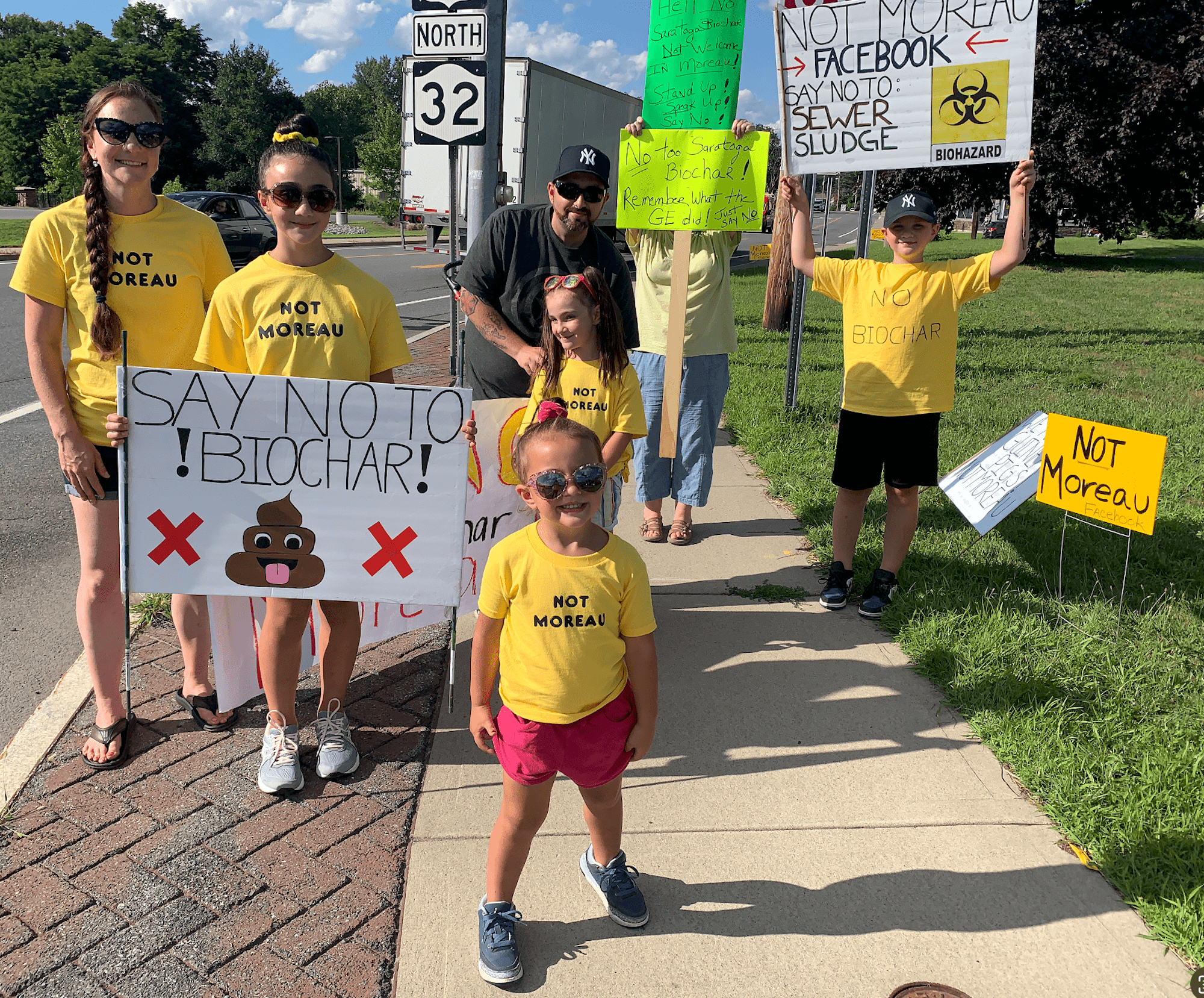 A group of kids hold signs against biochar