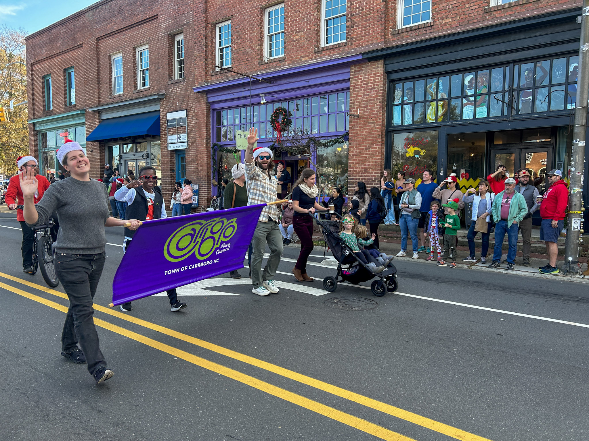 A group of people march with a Carrboro sign on a street