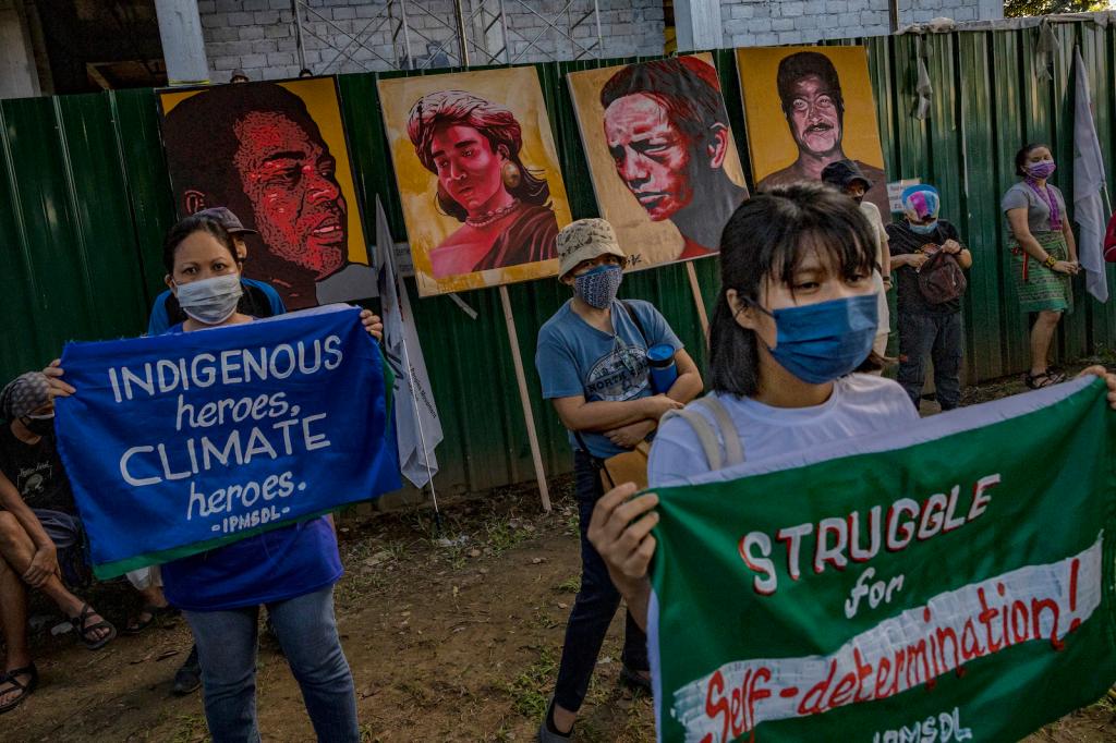 A group of climate protesters carry signs and portraits of Indigenous land defenders