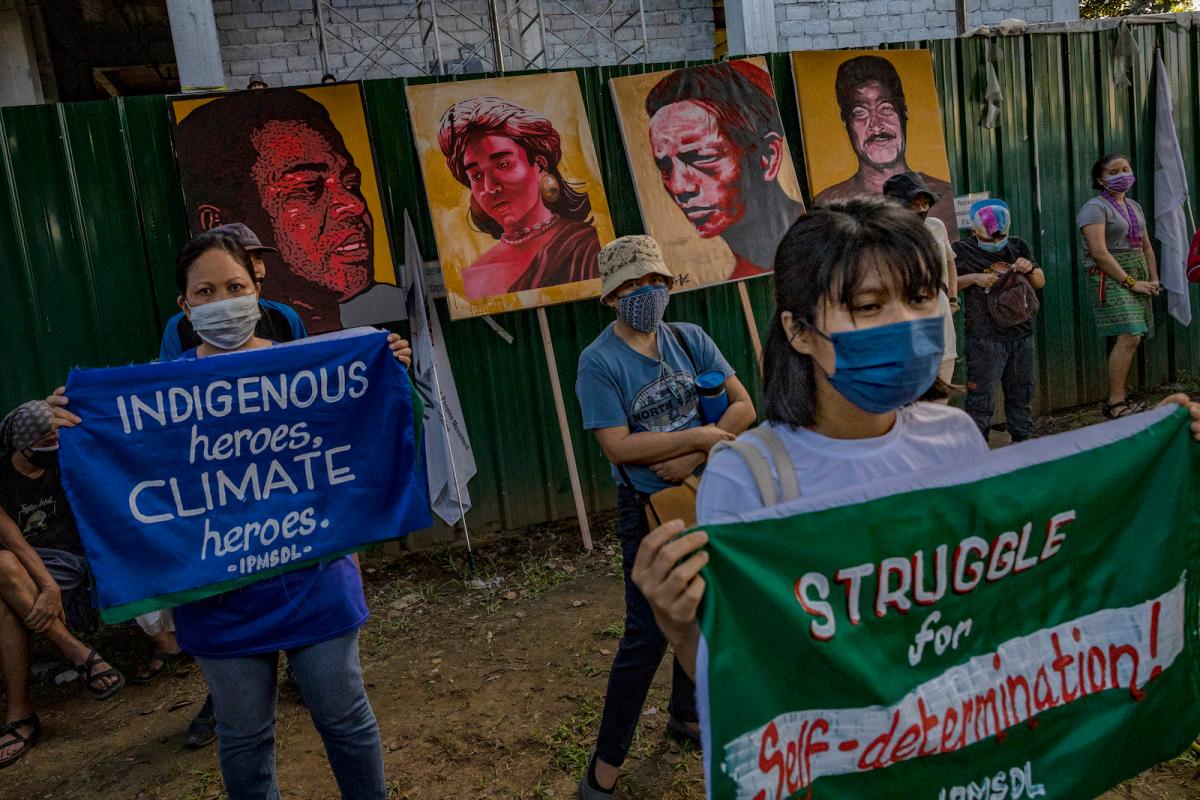 A group of climate protesters carry signs and portraits of Indigenous land defenders