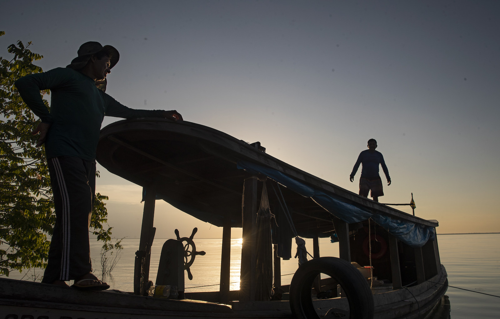 fishermen silhouetted against a boat at sunset or sunrise