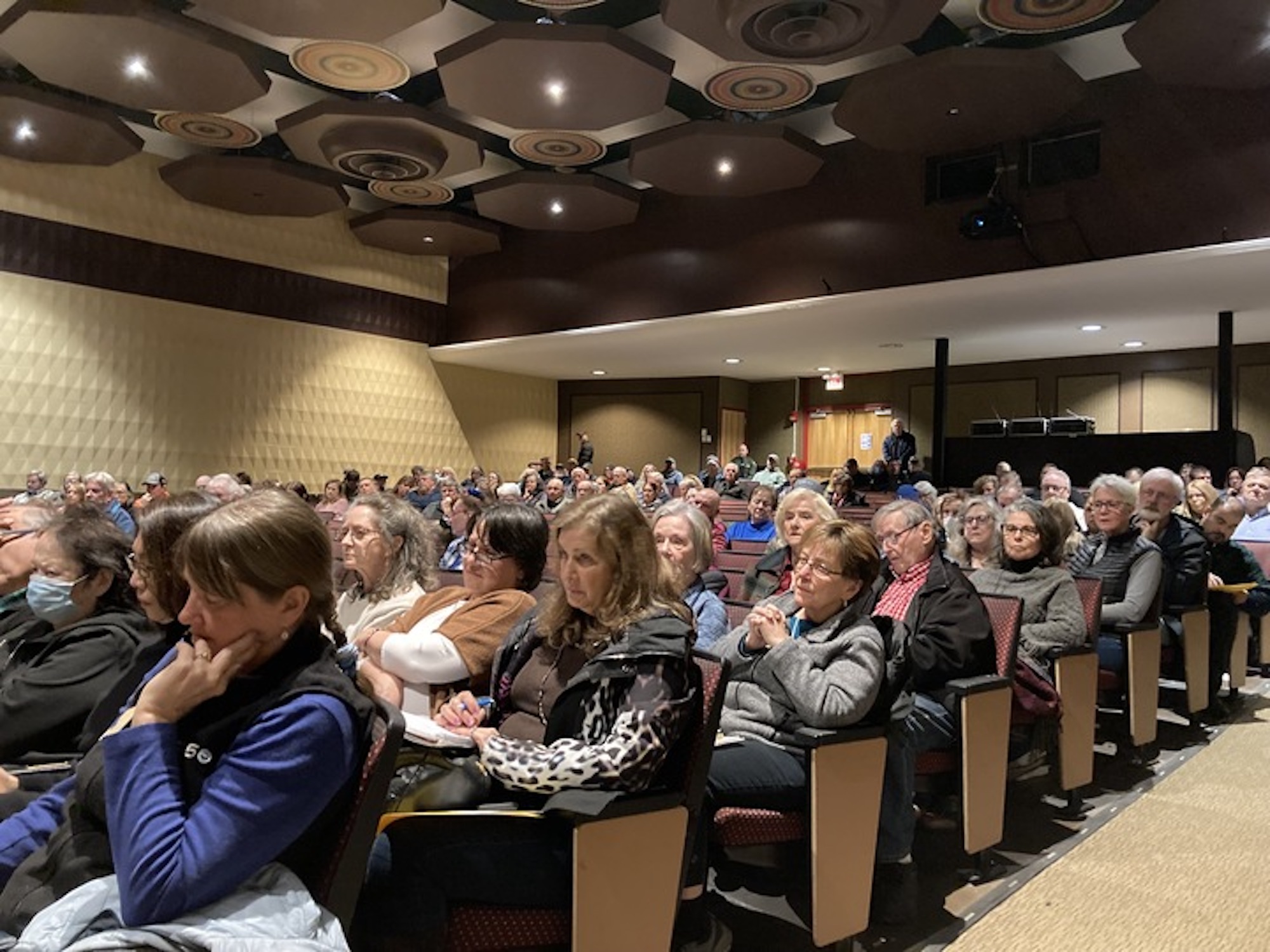 A group of people sit in a packed auditorium