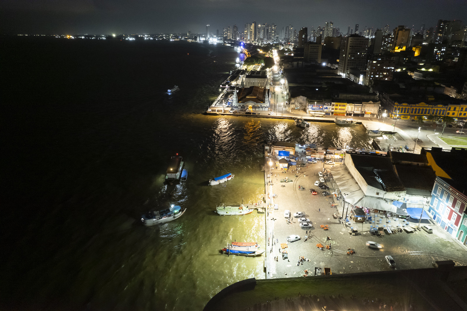 An aerial of a fishing town with lights and boats on the water at night