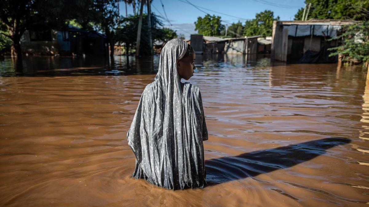 A woman wades through flood waters that inundated a residential area in Garissa, Kenya, following torrential rains in May, 2024.