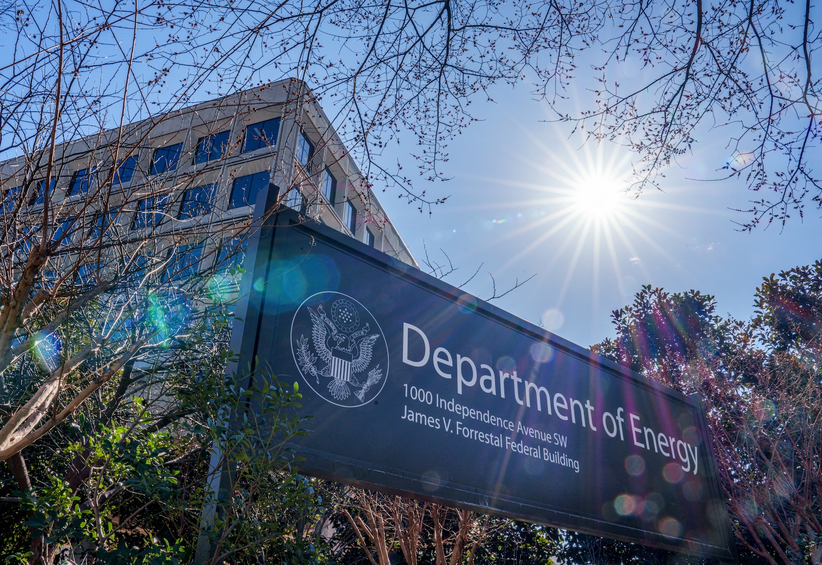 Blue sign reads "Department of Energy" in front of a tall office building