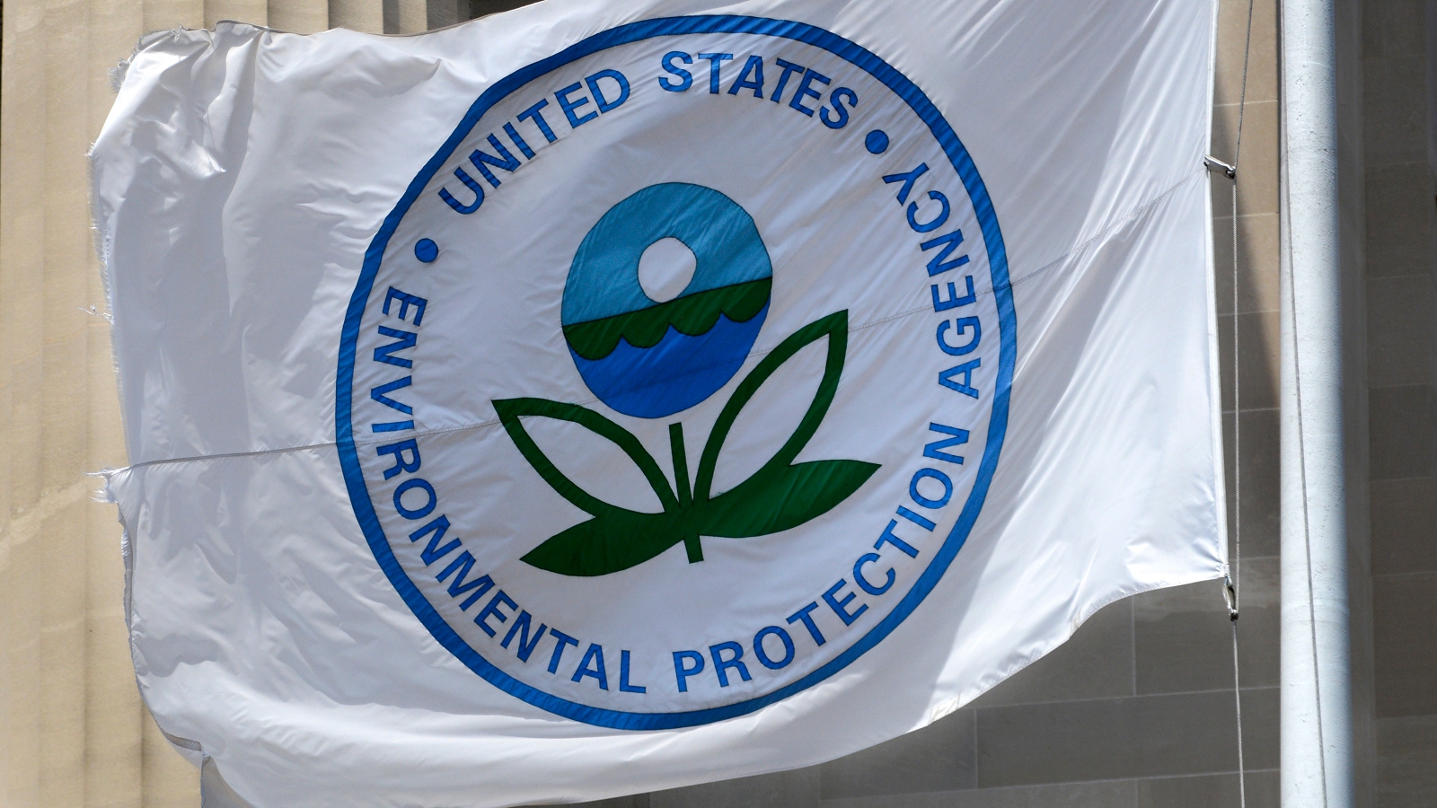 A white and blue Environmental Protection Agency flag flutters in front of EPA headquarters in Washington, DC.