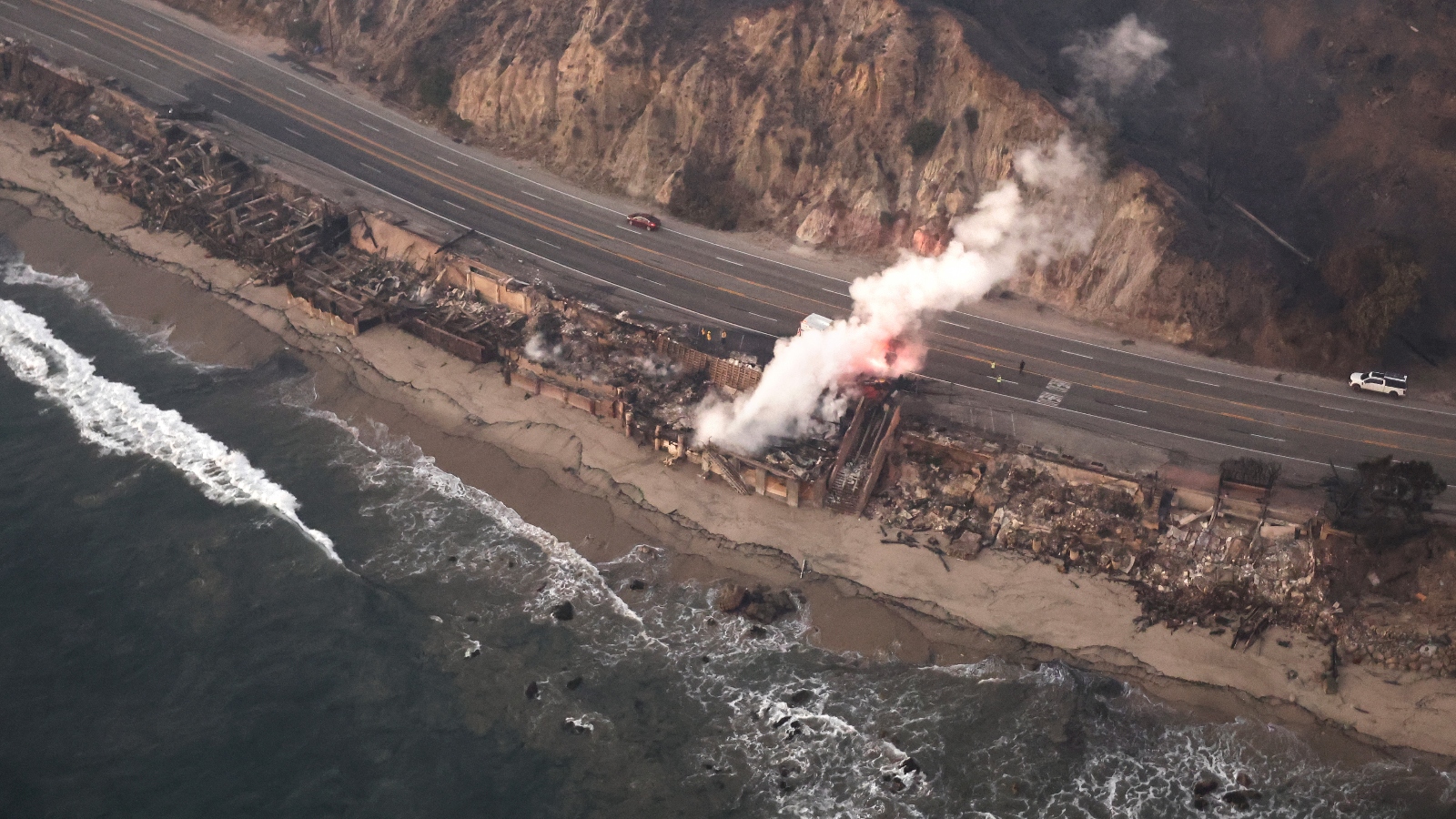 An aerial view of a wildfire burning home along the beach