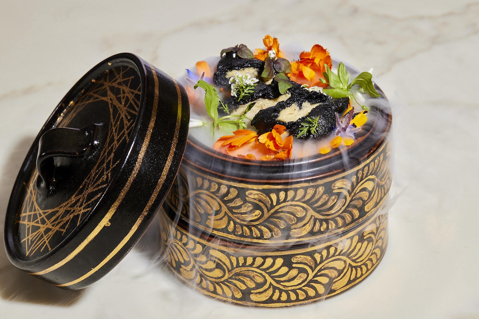 Tempura-battered ab-grown chicken is served in a gold dish with edible flowers and greens