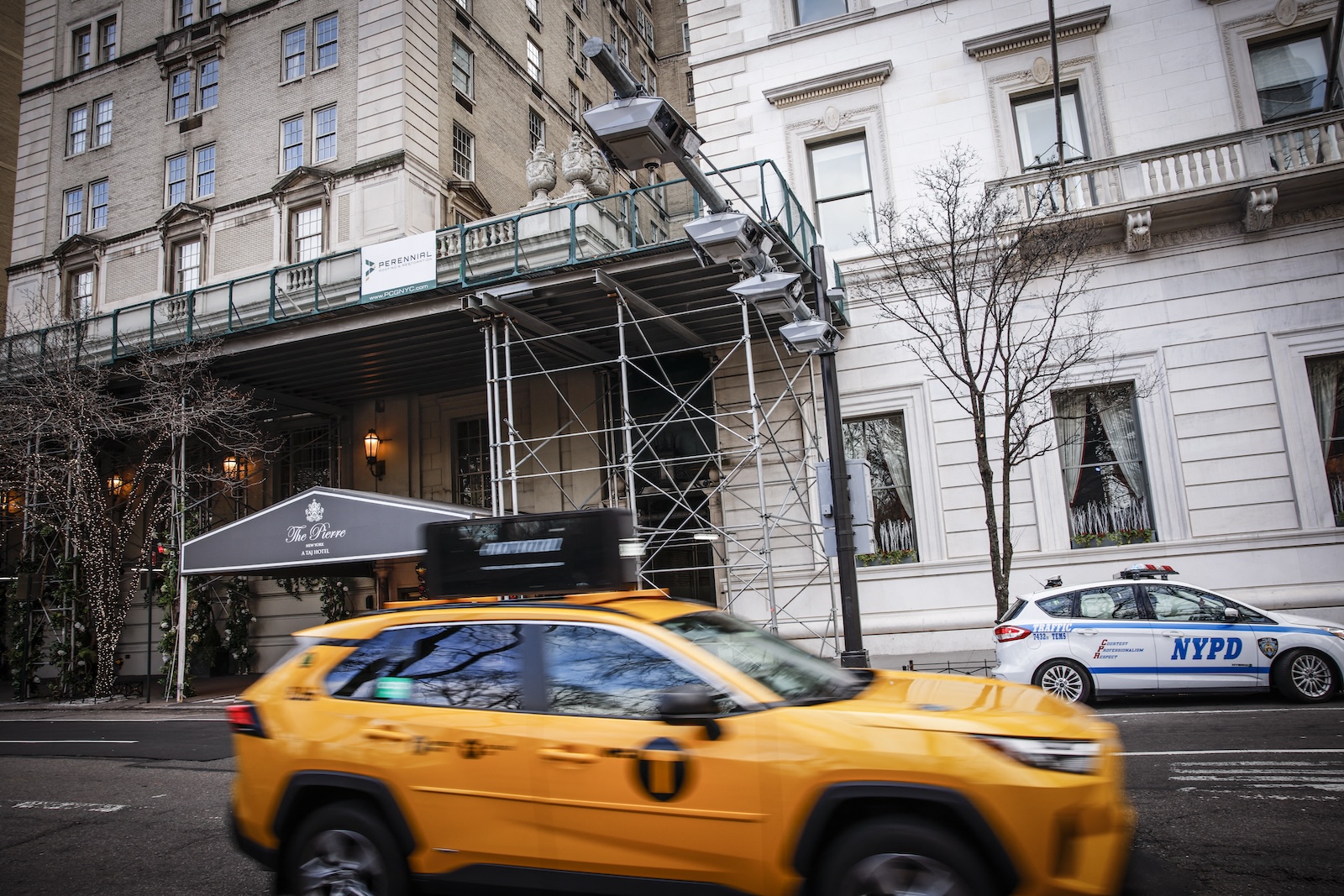 A yellow New York City taxicab goes by in front of a hotel