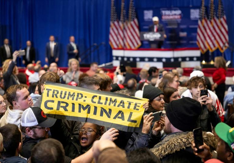 Photo of protesters at a Trump rally holding a sign saying that Trump is a climate criminal