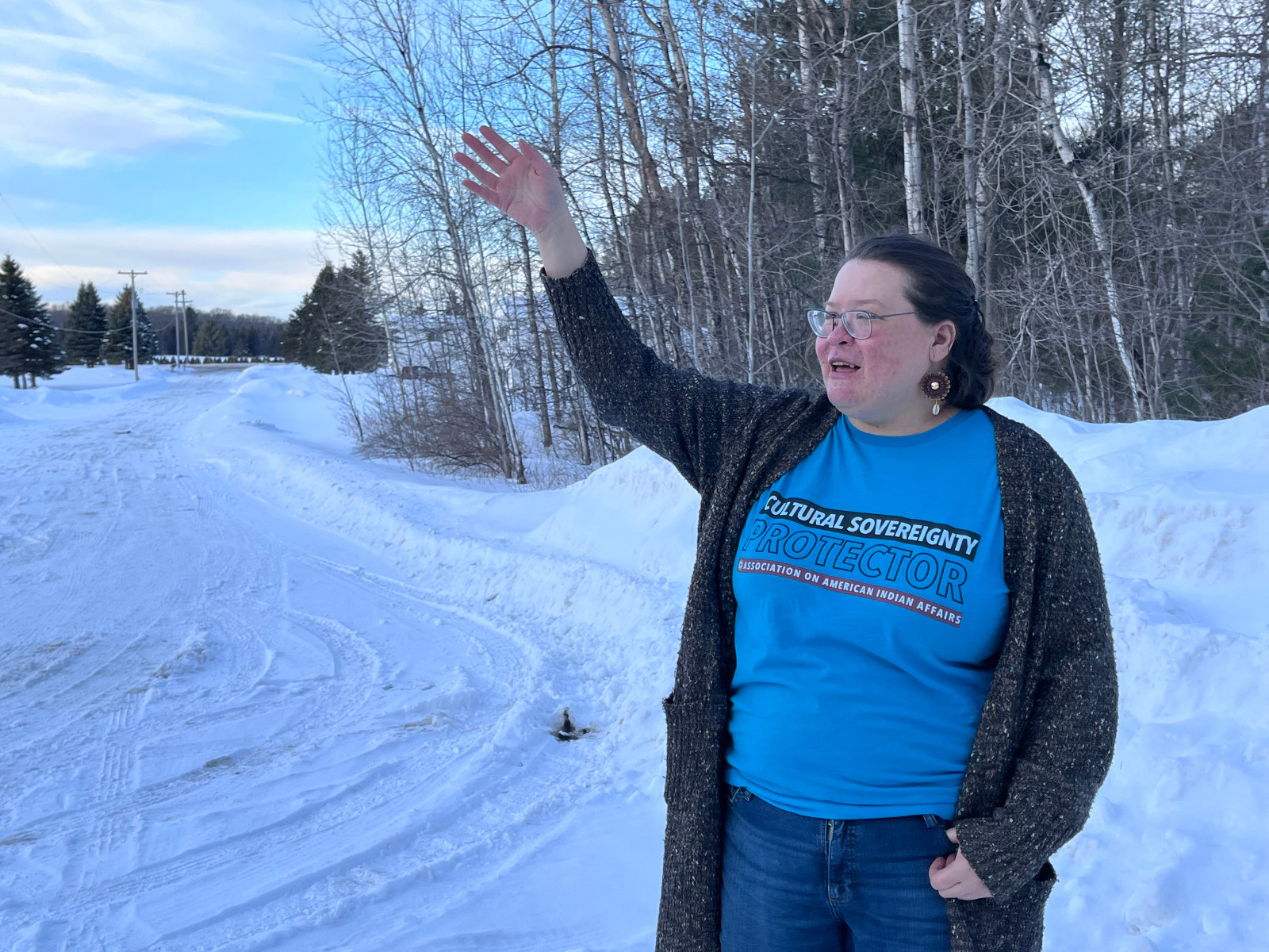 A woman points to the horizon in a snowy field.