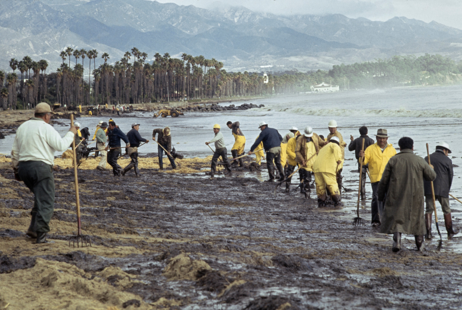 Foto von Crews, die bei einem Bruch mit Palmen und Bergen im Hintergrund dunkel, fettiger Boden rechnen