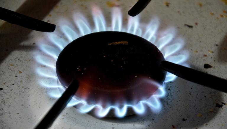 A closeup of the blue flames on a black gas stove burner