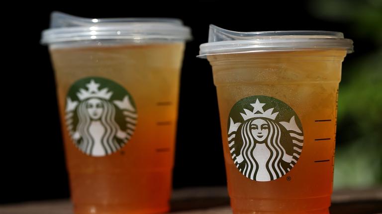 Two plastic Starbucks cups filled with orange liquid and ice.