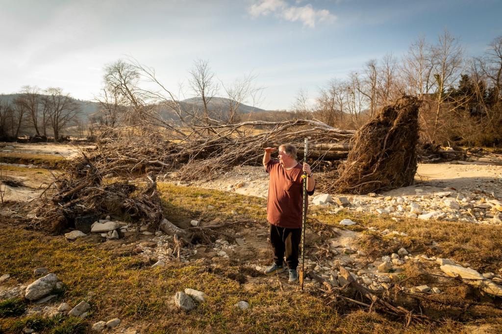 A man stands looking out in the distance on his farm