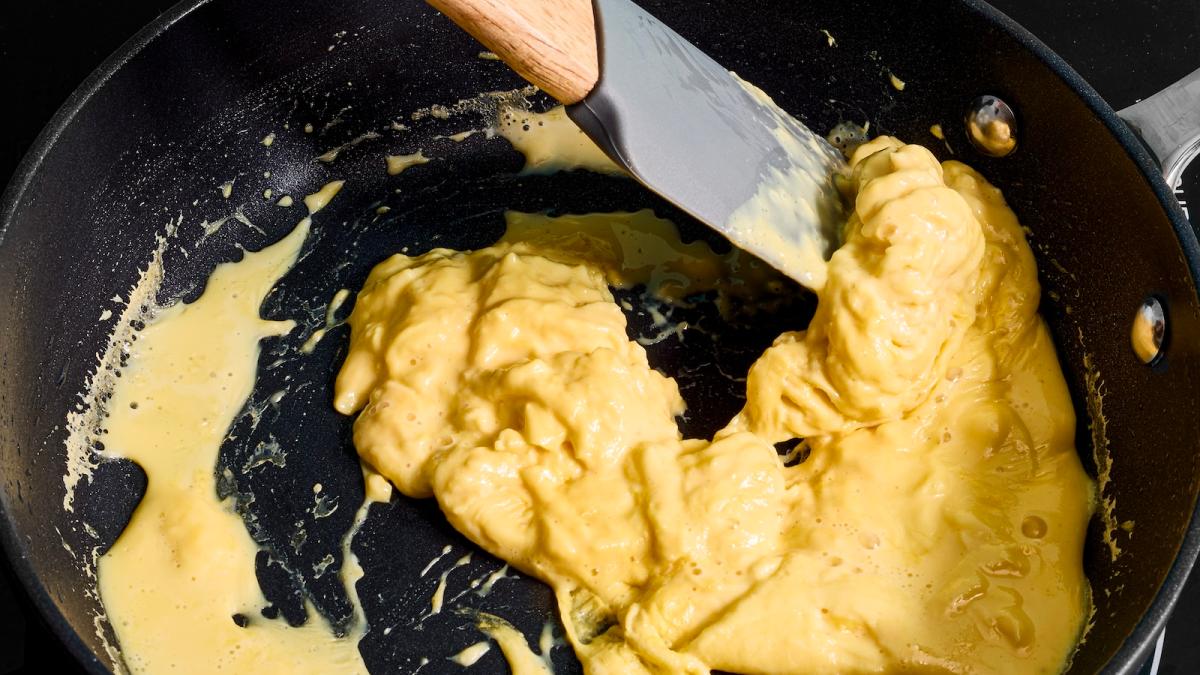 scrambled eggs (made from a vegan egg substitute) being moved around by a rubber spatula in a frying pan