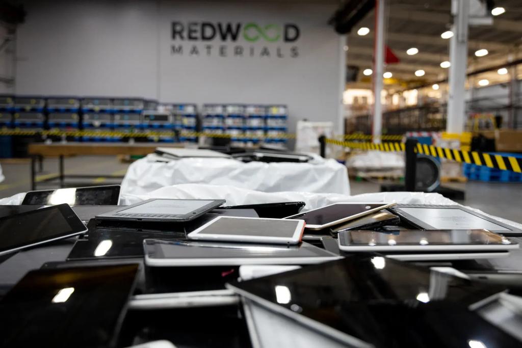 A pile of electronics in a warehouse with a sign indoors that says 'redwood materials'