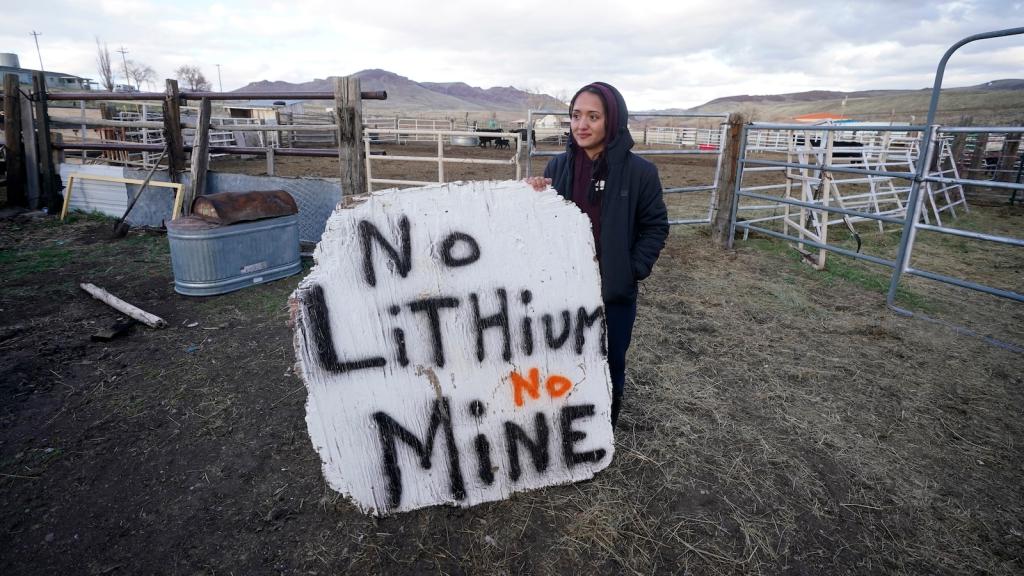 A woman stands next to a sign that says 