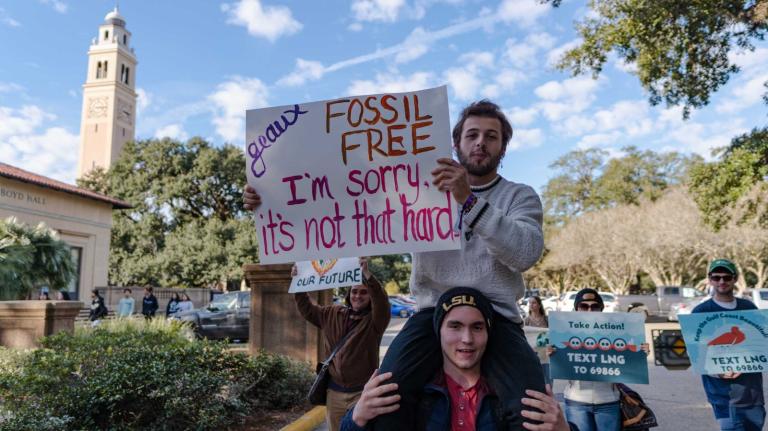 A Group of students march with a sign that says fossil free I'm sorry it's not that hard