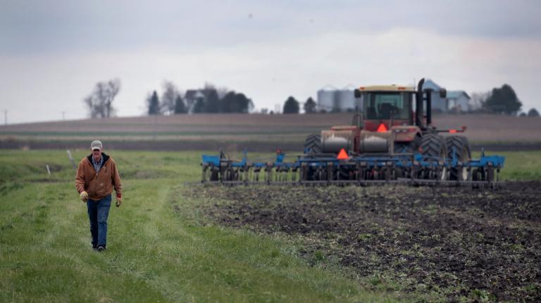 A farmer walks alongside a tractor