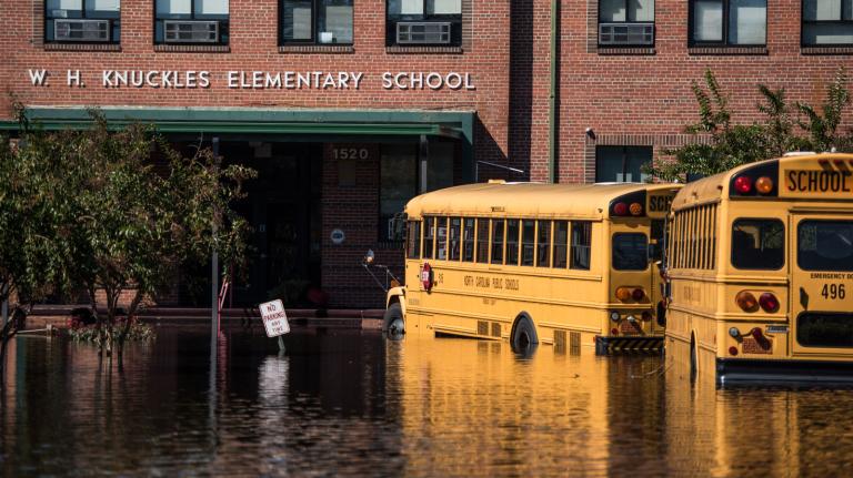 Photo of the outside of a flooded elementary school with school buses partially submerged