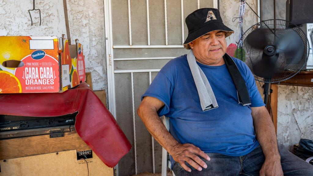 A man keeps cool on his porch ahead of his air conditioning unit installation during a heat wave