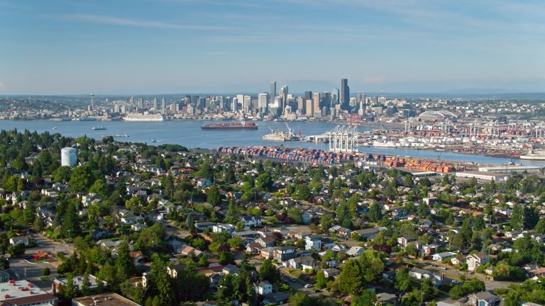 Aerial shot of Seattle, Washington on a sunny afternoon in summer, taken from above residential streets in West Seattle and looking across the bay towards the port and the downtown skyline