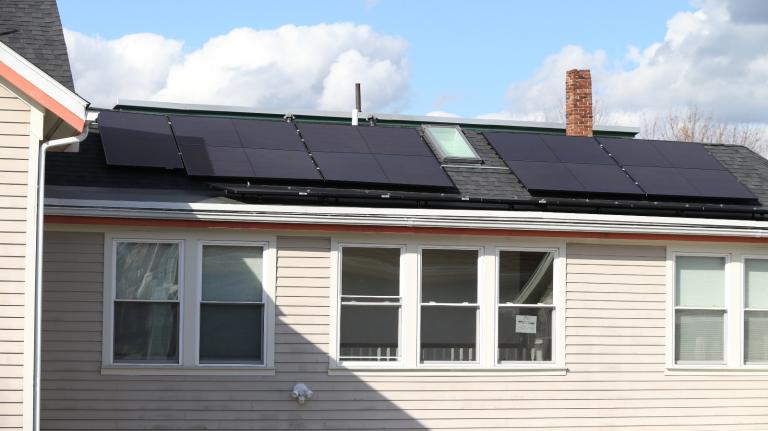A home with white siding has solar panels on the roof
