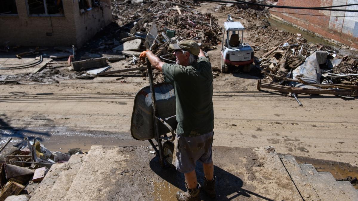 A man leans against a wheelbarrow while clearing debris from Marshall Presbyterian Church in Marshall, North Carolina, in the wake of Hurricane Helene.