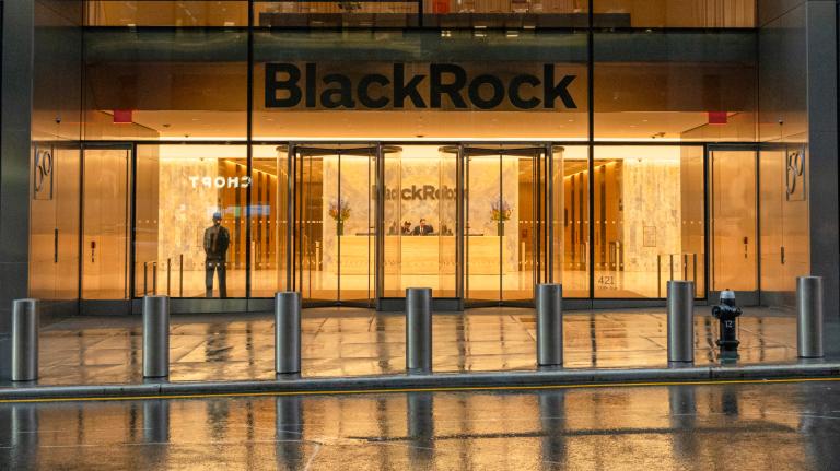 Photo of the mostly empty BlackRock building on a rainy night with orange light glowing from inside