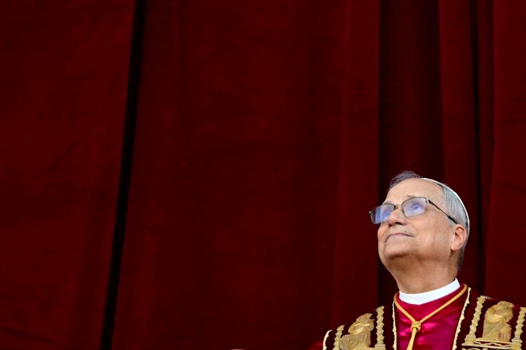 Pope Leo looks upwards in front of a red curtain
