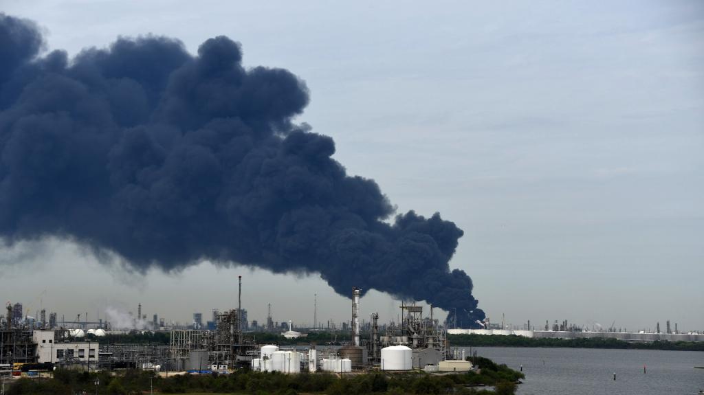 Black smoke billows across the sky as a chemical storage site burns in a fire.