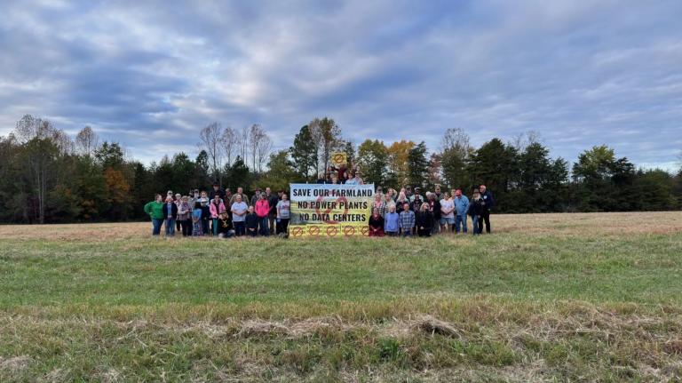A group of people in a field with a sign that says Save Our Farmland