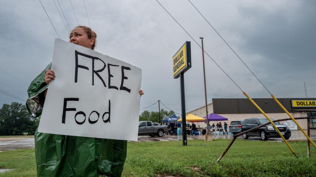 A volunteer displays a sign for free food for people in need of relief on July 06, 2025 in Center Point, Texas.