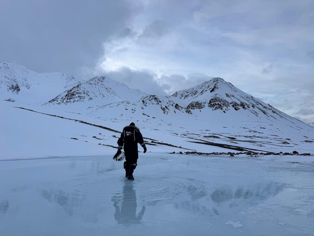 A lone human figure walks on melting ice in the Arctic