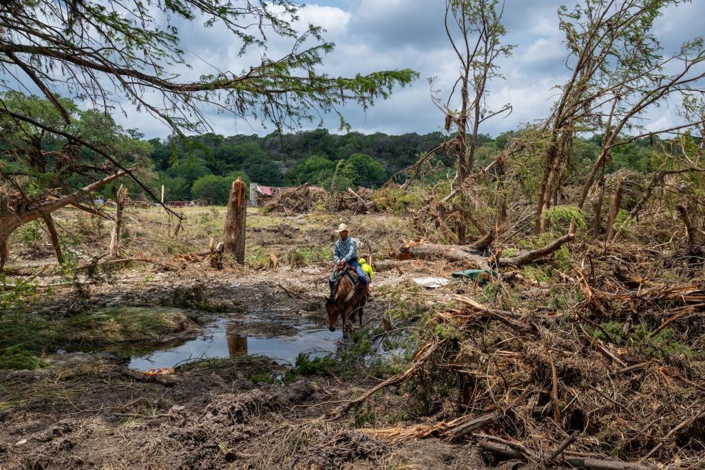 A man on a horse wades through flood debris
